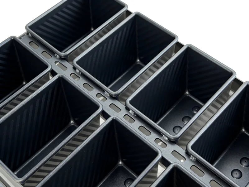 A technician measuring a custom baking pan with calipers