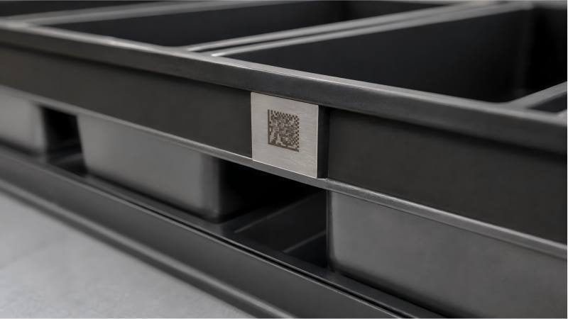 A close-up of a laser-etched Data Matrix code on the corner of a baking pan