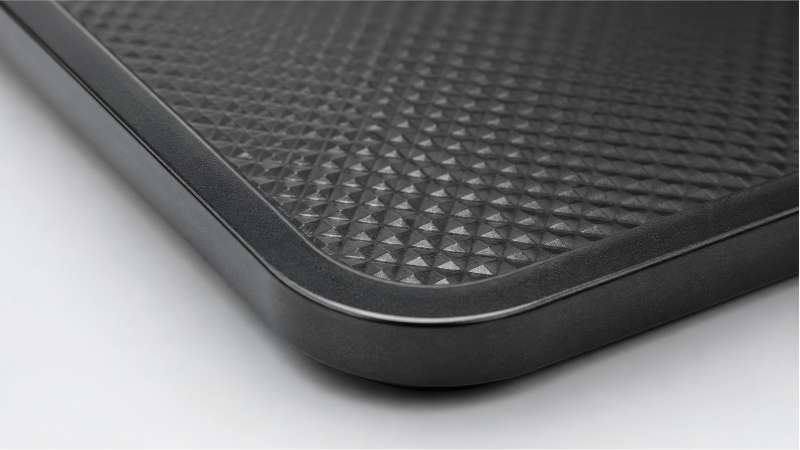 A close-up view of the edge of a thick, heavy-duty baking pan