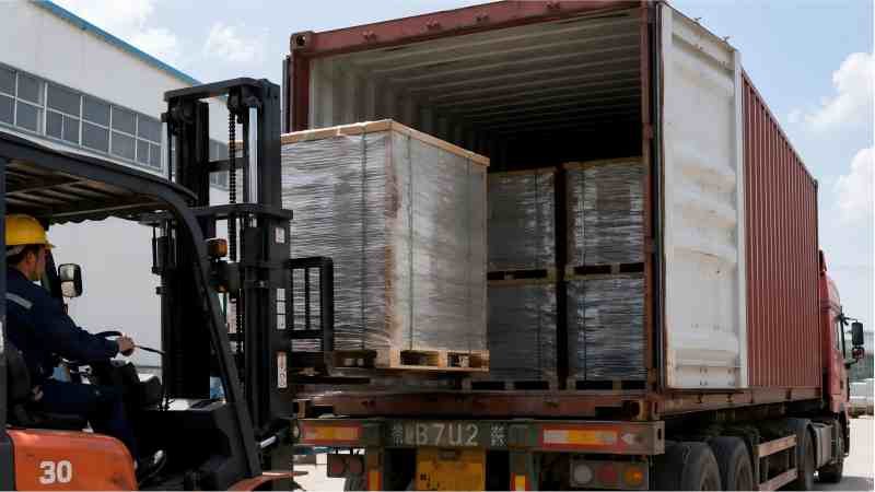 A shipping container being loaded with boxes of bakery equipment