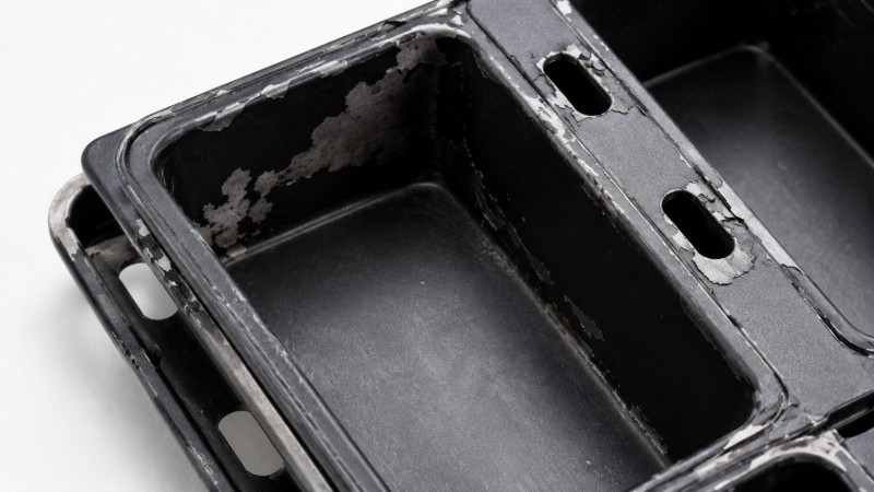 A close-up of a peeling non-stick coating on a baking pan